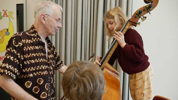 Ein Kind spielt Kontrabass, Musiker Martin Lillich unterstützt dabei (Quelle: rbb/OHRENBÄR/Jakob Senger)