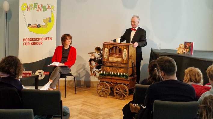 Autorin Lena Hach und Manfred Grabowski an der Drehorgel, im Hintergrund Aufsteller mit OHRENBÄR-Logo (Quelle: rbb/OHRENBÄR/Sonja Kessen)