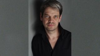 Porträt des Schauspielers Uwe Neumann, an einer Wand gelehnt, mit Schatten (Quelle: Anette Daugardt)